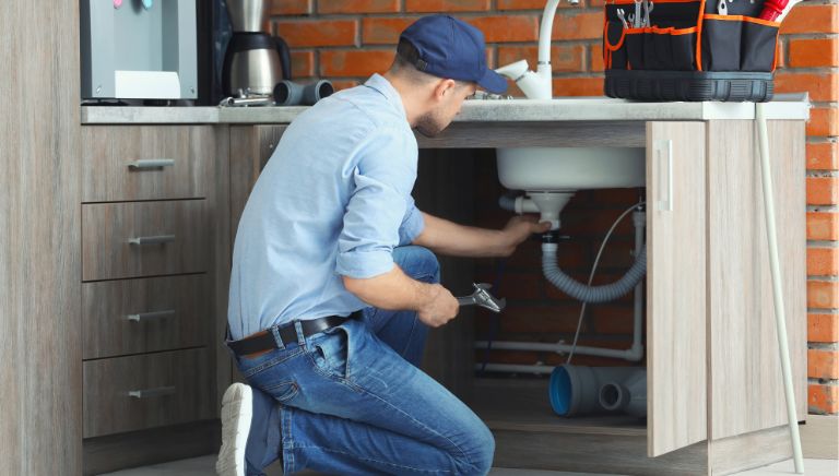 A plumber is repairing a sink